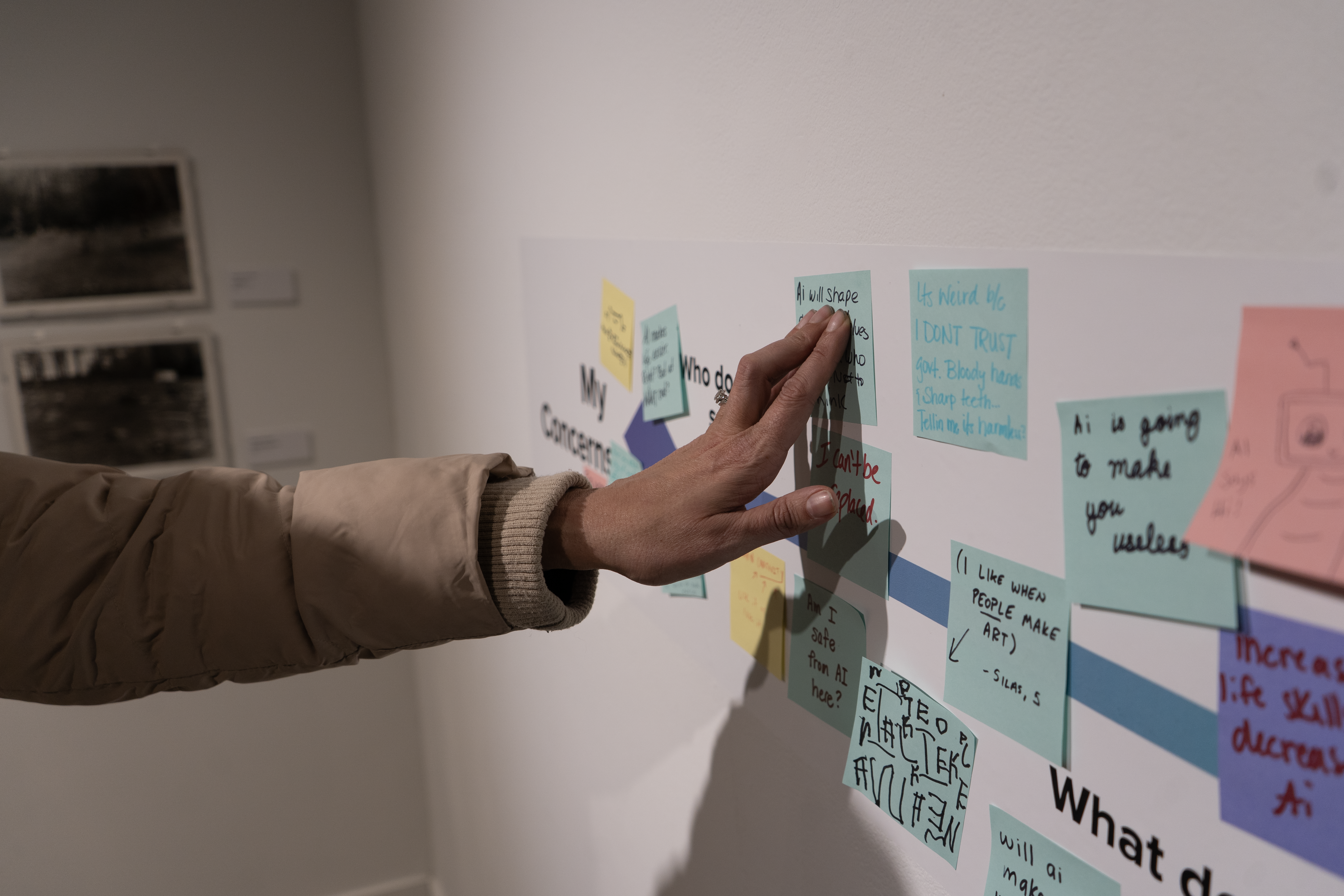Hand touching a sticky note on the gallery wall