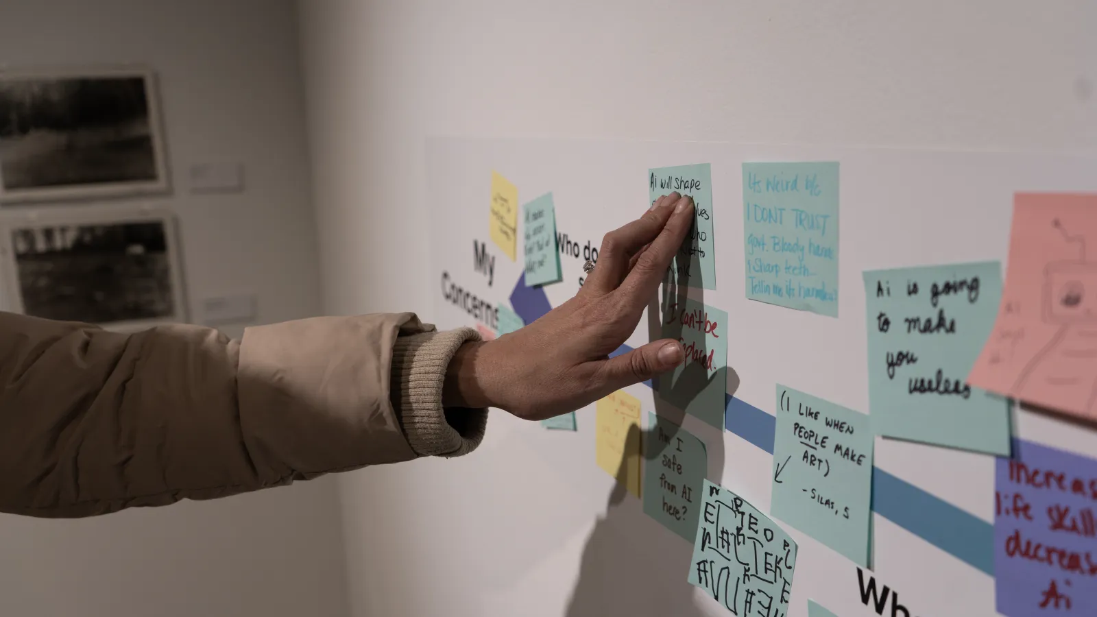 Hand touching a sticky note on the gallery wall