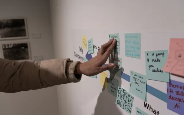 Hand touching a sticky note on the gallery wall