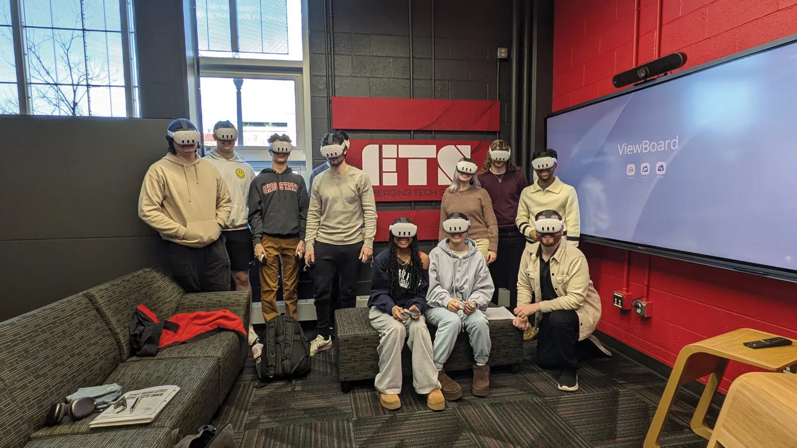 Students and their instructor wearing VR headsets in front of a red ETS sign