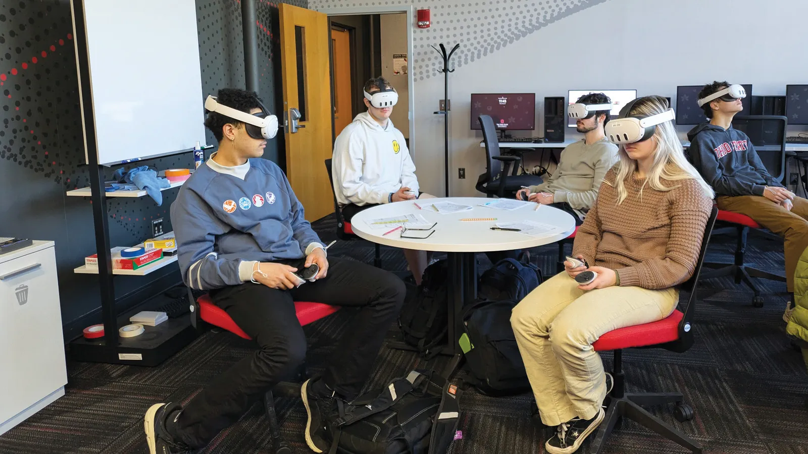 A group of students sitting around a table wearing VR headsets